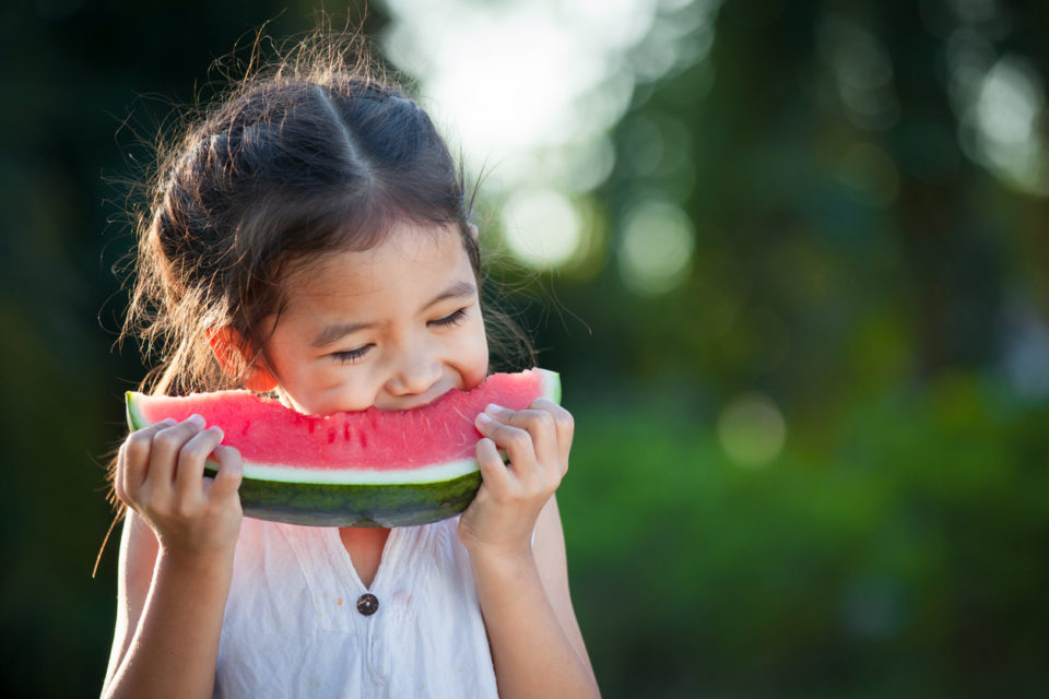 Little girl eating a slice of watermelon outside