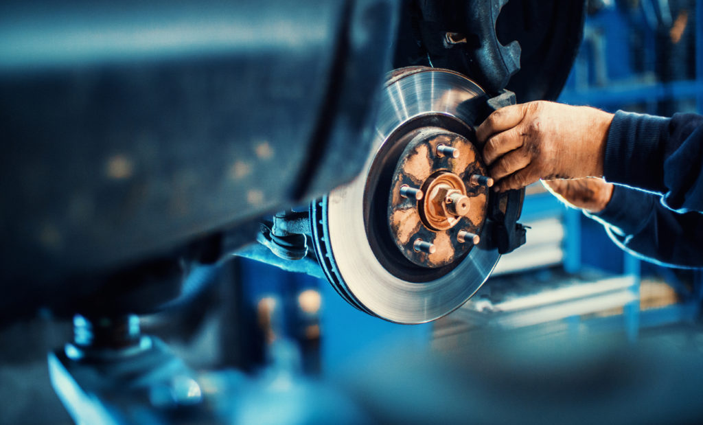 Closeup of hands replacing car brake pads.