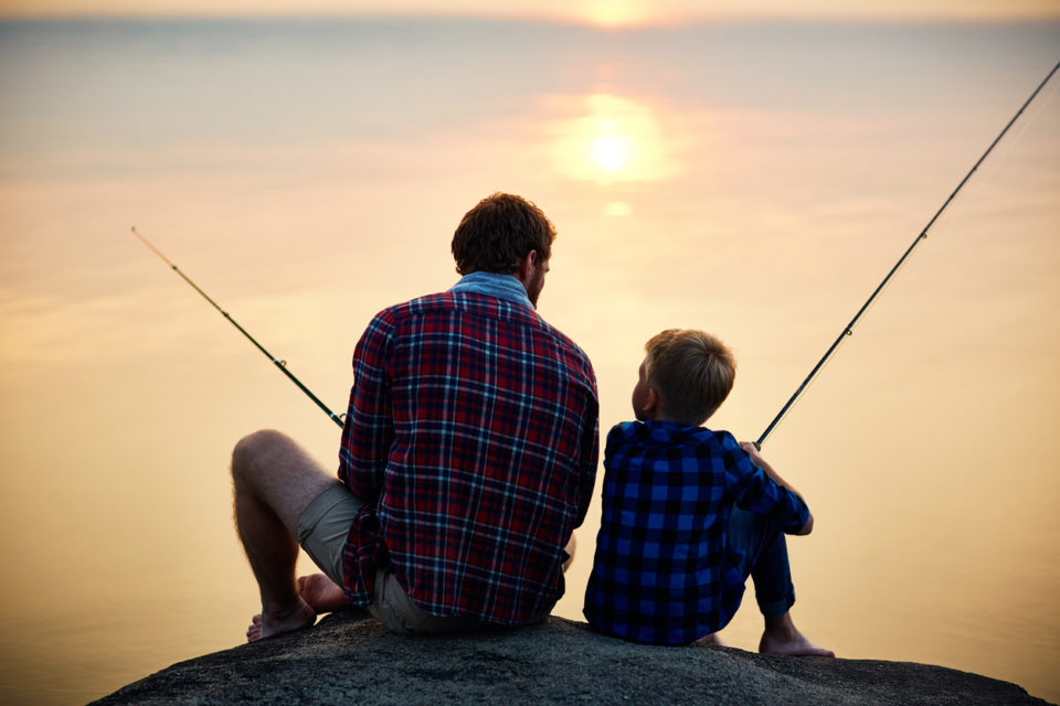 Father and son fishing at sunset