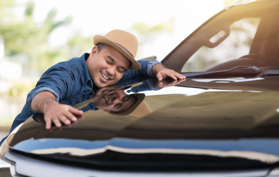 young man hugging car exterior