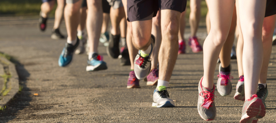 Runners racing a local 5K around a lake on a dirt path on a early summer evening.