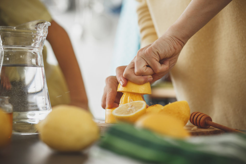 Woman squeezing juice and making lemonade in the kitchen.