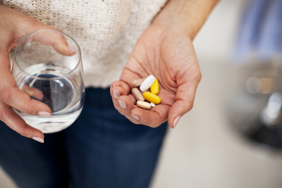 woman holding vitamins in one hand and water in the other
