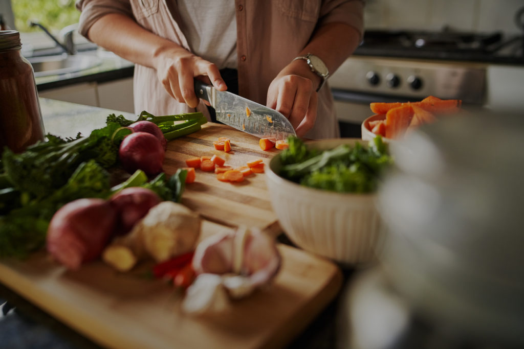 Female hands cutting vegetables on cutting board