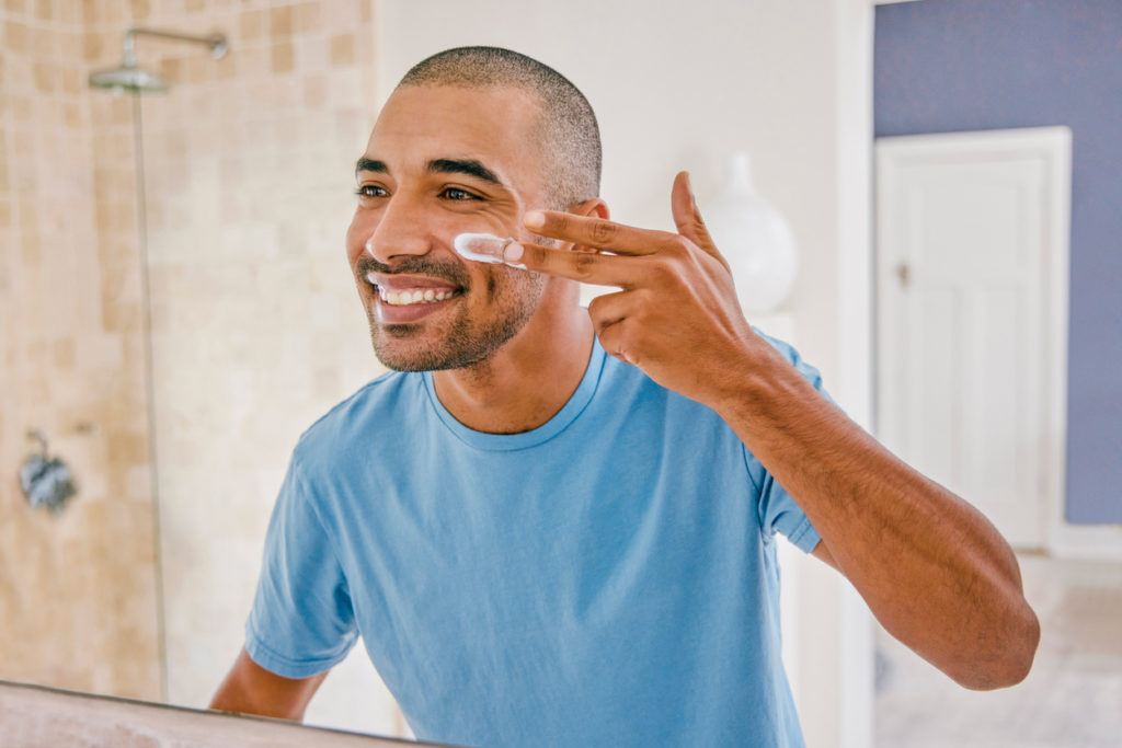 young man applying cream on face