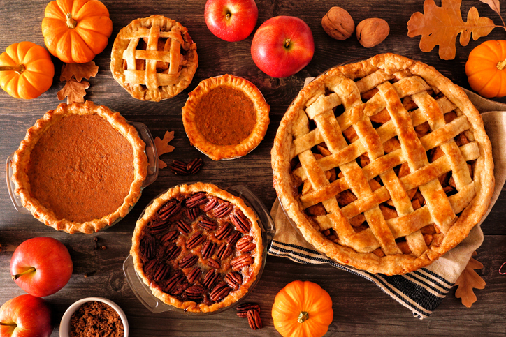 Variety of homemade autumn pies. Apple, pumpkin and pecan. Top down view table scene on a rustic wood background.