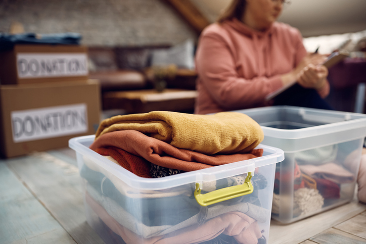 Donation box with clothes with a volunteer in the background.