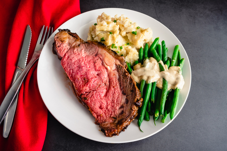 Medium-rare prime rib dinner served with side dishes on a white plate